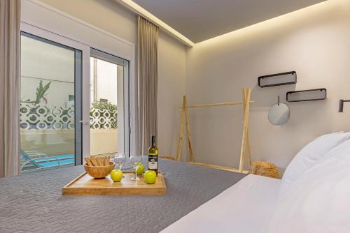 a bedroom with a bed with a bottle of wine and fruit at Elia & Anthos Deluxe Suites in Ixia