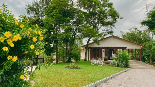 a small house with a garden and a yard at Seu Refúgio Rural Piscina Privativa e Natureza in Tubarão