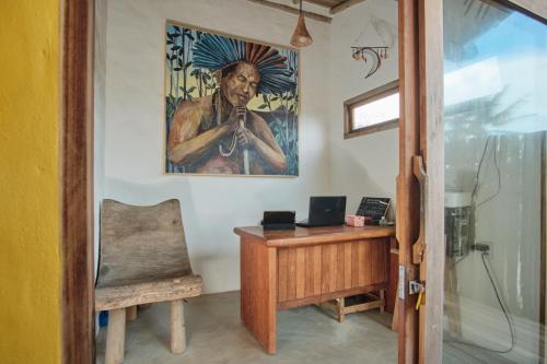 an office with a desk and a painting on the wall at Tamikuã Mar Pousada in Caraíva