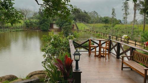 a wooden bridge over a river with a table and benches at Seu Refúgio Rural Piscina Privativa e Natureza in Tubarão
