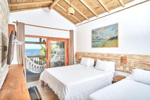 two beds in a room with a balcony at Tamikuã Mar Pousada in Caraíva