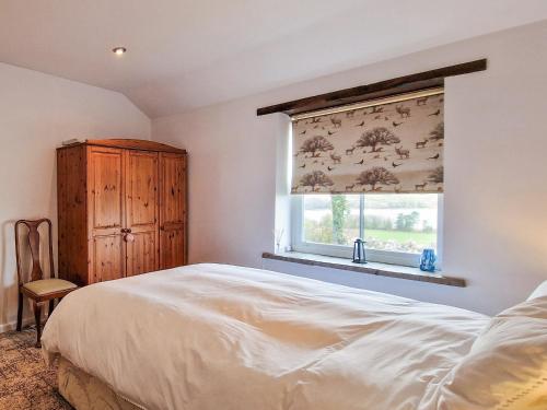 a bedroom with a bed and a window with a curtain at The Barn in Blagdon
