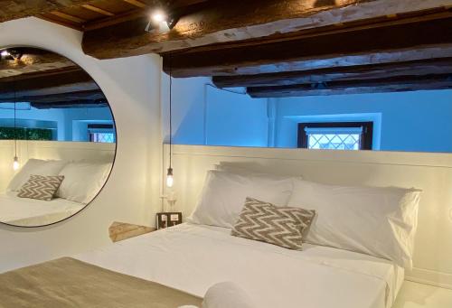 a bedroom with a white bed and a mirror at Il Barchio loft in un palazzo di fine 800 a Jesi in Iesi