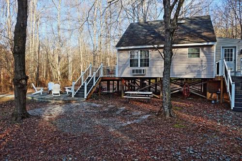 a house with a porch and a deck with two chairs at Our Private Wooded Cabin in Chatham