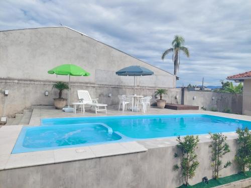 a swimming pool with a table and chairs and umbrellas at Casa Aconchego - piscina com hidromassagem in Guaratuba