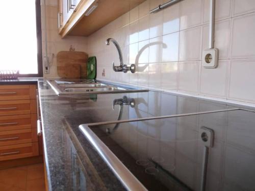 - une cuisine avec évier en acier inoxydable et comptoir dans l'établissement Apartamento Areias Mar, à Albufeira