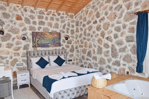 - une chambre aux murs en pierre avec un lit et une baignoire dans l'établissement Villa Harmony, à Fethiye
