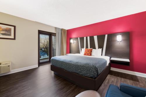 a bedroom with a large bed with a red wall at Econo Lodge Inn & Suites on the River in Gatlinburg