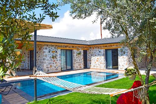 - un hamac en face d'une maison avec une piscine dans l'établissement Villa Harmony, à Fethiye