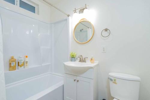 Baño blanco con lavabo y espejo en Stylish 2B2B country style house en Glendora