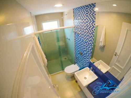 La salle de bains est pourvue d'une douche bleue et blanche ainsi que de toilettes. dans l'établissement Villa Giuliano no Hibiscus Beach Clube Ipioca Maceio, à Maceió