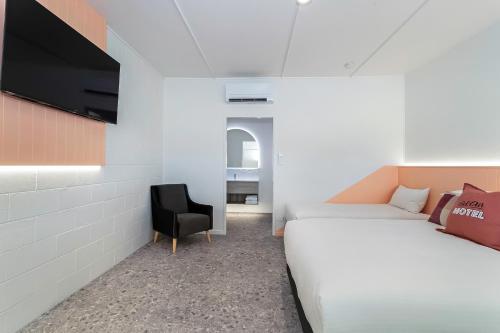 a bedroom with a bed and a chair and a tv at Bel Air Motel in Mackay