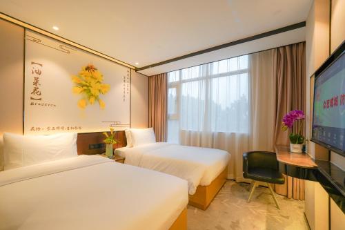 a hotel room with two beds and a flat screen tv at Guangdong Baiyun City Hotel in Guangzhou
