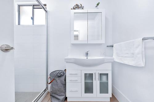 y baño blanco con lavabo y ducha. en Studio 8 on Waterson, en Airlie Beach