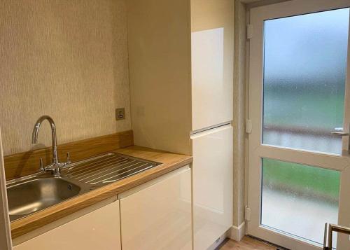uma cozinha com um lavatório, um frigorífico e uma janela em Badgers Retreat Holiday Park em Hunton