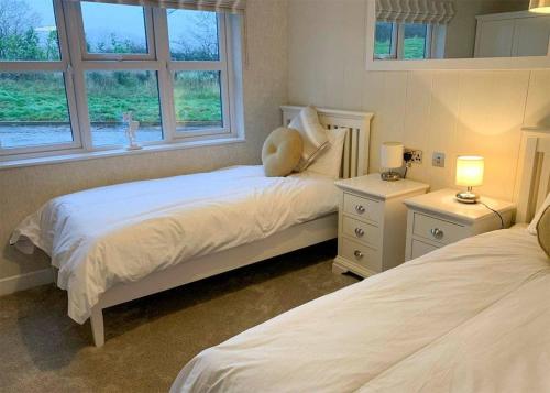 a bedroom with two beds and two windows at Badgers Retreat Holiday Park in Hunton