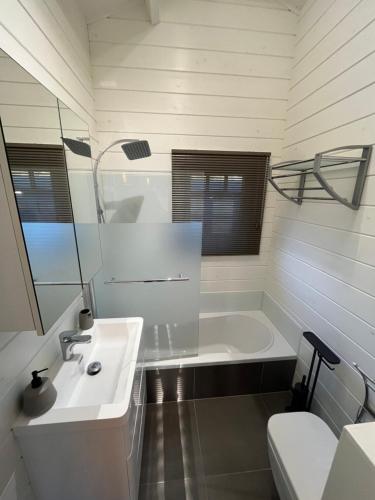 een badkamer met een wastafel, een bad en een toilet bij Welkom bij Mario, Een charmante Chalet gelegen aan een vijver in bosrijke omgeving waar je tot rust kan komen. 