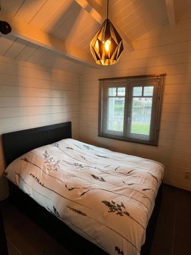 a bedroom with a bed and a chandelier at Welkom bij Mario, Een charmante Chalet gelegen aan een vijver in bosrijke omgeving waar je tot rust kan komen. 