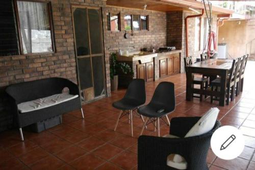 a living room with black chairs and a kitchen at Loft Alajuela in Alajuela City