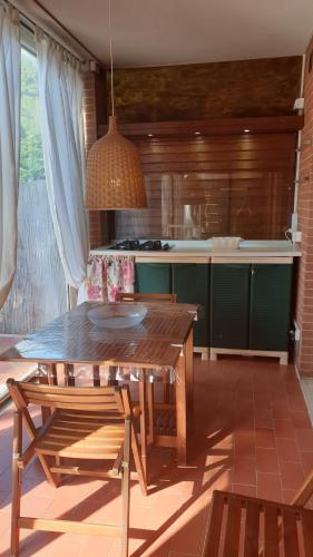 una cucina con tavolo in legno, alcune sedie e un tavolo di Casa in affitto a Marina di Grosseto a soli 150 metri dal mare a Marina di Grosseto