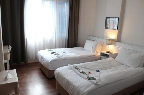 a hotel room with two beds and a window at Urkmez Hotel in Selcuk