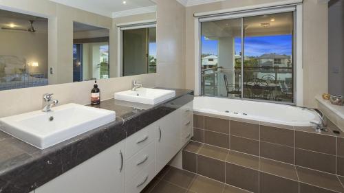 een badkamer met 2 wastafels en een bad bij Luxury waterfront house close to Theme Parks and shops in Gold Coast