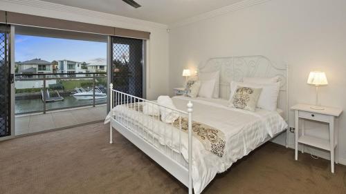 a white bedroom with a bed and a balcony at Luxury waterfront house close to Theme Parks and shops in Gold Coast