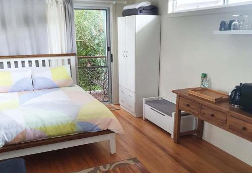 a bedroom with a bed and a desk and a window at Mullumbimby Studio in Mullumbimby