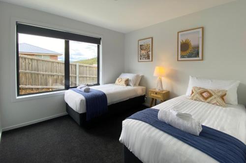 two beds in a room with a window at Albatross Rise - Modern Family Home in Hobart