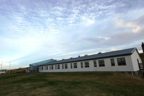 un bâtiment blanc avec un toit bleu sur un champ dans l'établissement North Star Staðarflöt, à Hvammstangi