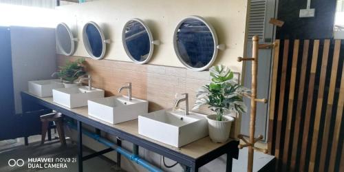 a row of sinks in a bathroom with four mirrors at บ้านโอเค โฮสเทล OK HOME hostel in Ban Khlong Thewa