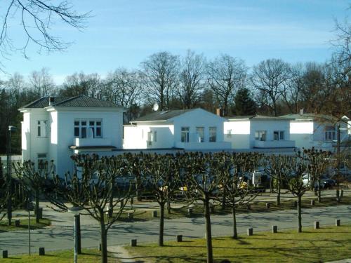 a white building with trees in front of it at Hotel Sonnenklause in Travemünde