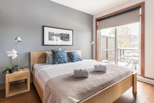 1 dormitorio con 1 cama con almohadas azules y balcón en Suites sur Lac Superieur-Mont-Tremblant en Lac-Superieur