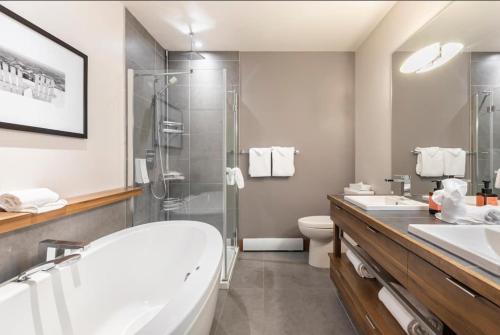 a bathroom with a tub and a shower and a sink at Suites sur Lac Superieur-Mont-Tremblant in Lac-Superieur