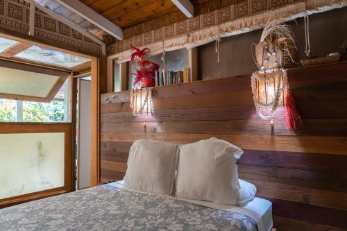 - une chambre avec un lit et un mur en bois dans l'établissement Le Charme Polynésien proximité plage et commerces, à Punaauia