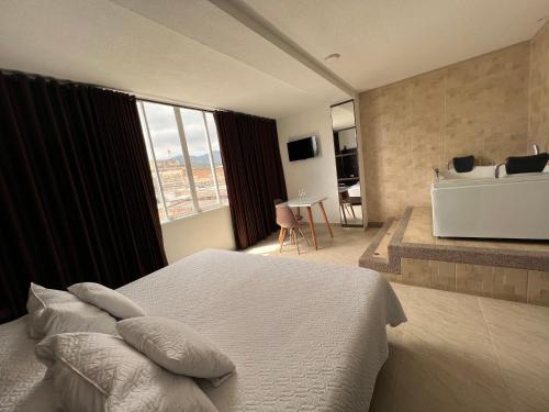 a bedroom with a bed and a bathroom with a tub at Hotel Marialu in Ocaña