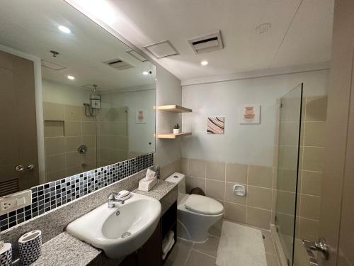 a bathroom with a sink and a toilet and a mirror at Alea Residences in Manila