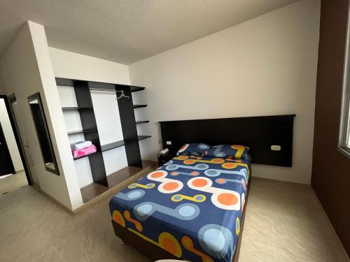 um quarto com uma cama com um edredão colorido em Hotel Marialu em Ocaña