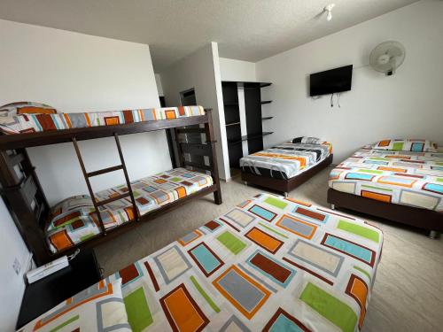 a room with two bunk beds and a flat screen tv at Hotel Marialu in Ocaña