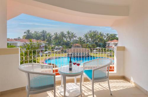a balcony with a table and chairs and a pool at Heritage Village Resort & Spa Goa in Cansaulim