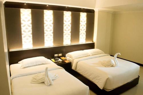 Dos camas en una habitación de hotel con cisnes. en M Citi Suites, en Cebú