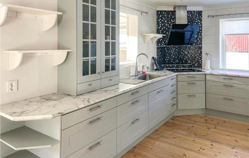 a white kitchen with white cabinets and a sink at Awesome Home In Idkerberget With Lake View in Grangärde