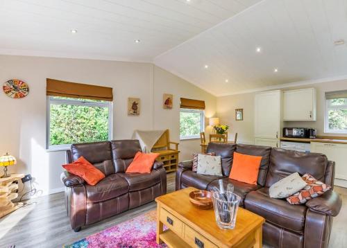 a living room with two leather couches and a coffee table at Meadows End Lodges in Cartmel
