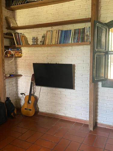 盧漢的住宿－Casa de campo con laguna y piscina，砖墙上的电视,旁边是吉他