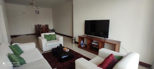 ein Wohnzimmer mit weißen Möbeln und einem Flachbild-TV in der Unterkunft Asian Residencies @ Trillium, Colombo 7 in Colombo