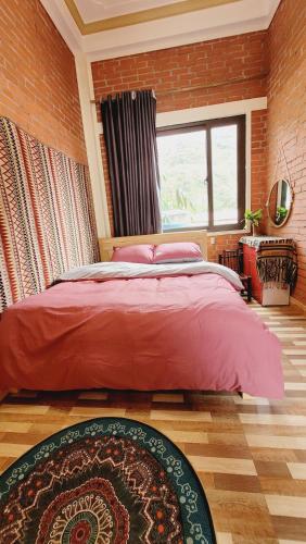 a bedroom with a red bed and a brick wall at Du Gia View Homestay in Làng Cac
