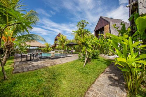 a resort yard with a swimming pool and grass at BB Garden Resort in Canggu