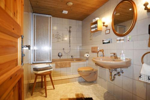 a bathroom with a sink and a toilet and a tub at Obersteinberg-Hof in Ruhpolding