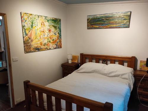 a bedroom with a bed and two paintings on the wall at Sweetwater Cottage. A private mountain escape in Upper Burringbar