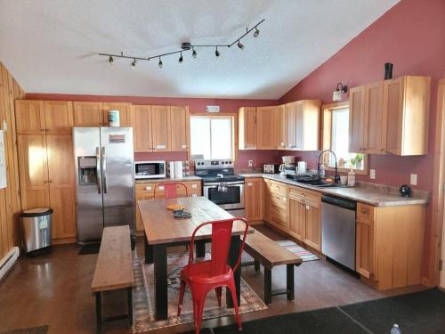 a kitchen with wooden cabinets and a table with red chairs at Marshmallow home in Gilmour